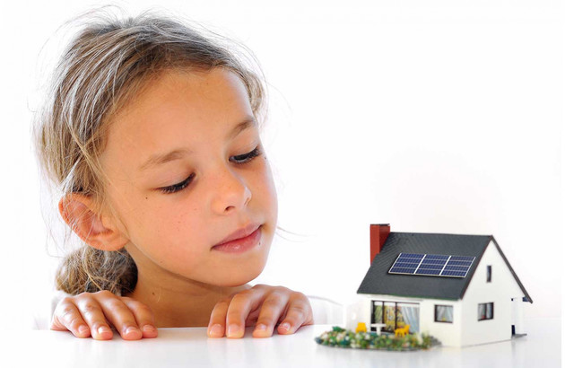 fille regardant maison aux panneaux solaires miniature