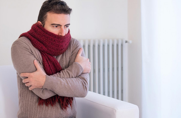 Homme avec écharpe devant radiateur en panne