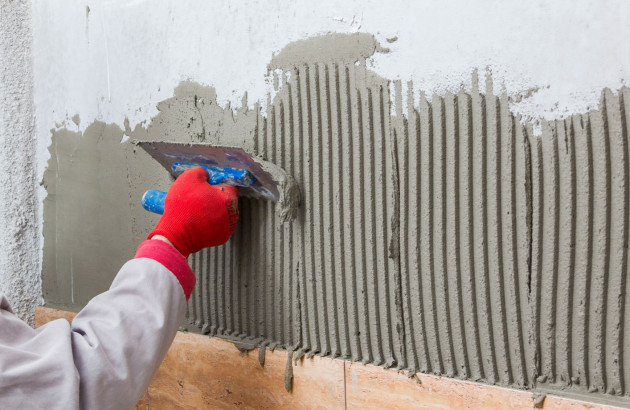 Travail de la surface sur un mur avant la pose du carrelage en quinconce