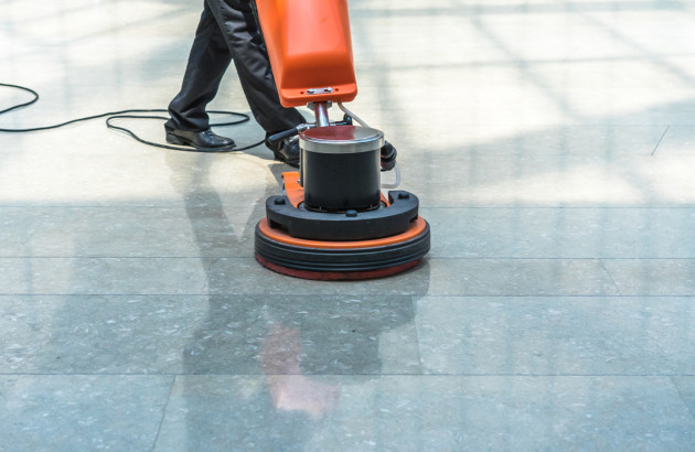 Homme utilisant une cireuse-lustreuse sur du carrelage