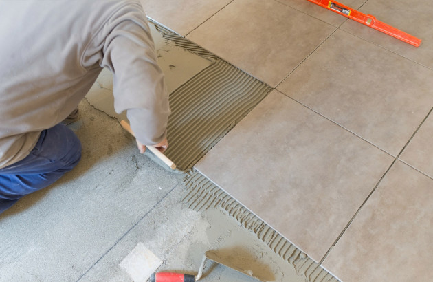 Artisan posant du carrelage au sol
