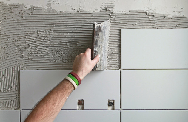 Artisan posant du carrelage mural blanc