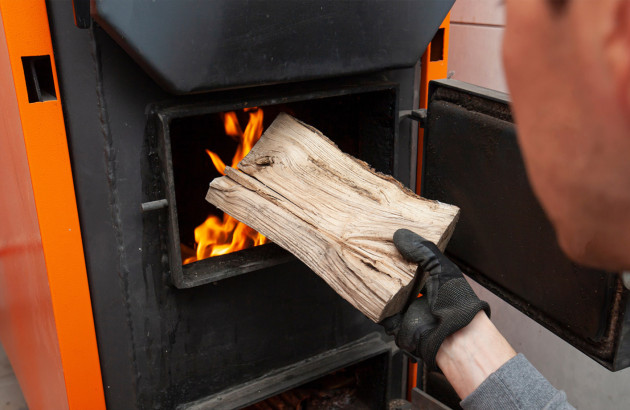 Homme qui met une bûche de bois dans une chaudière bois