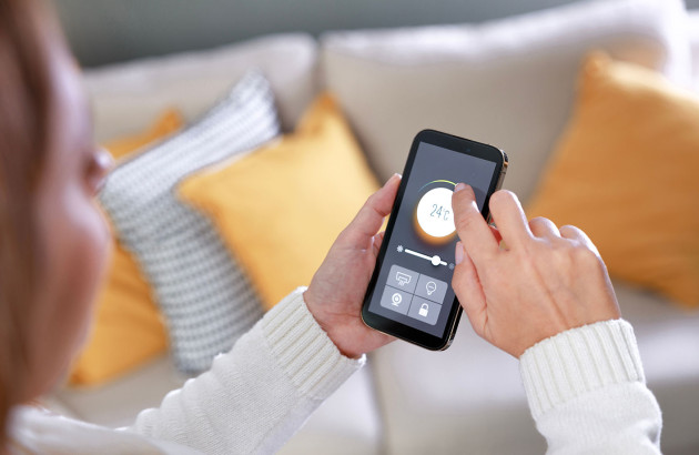 jeune femme utilisant son smartphone pour régler la température
