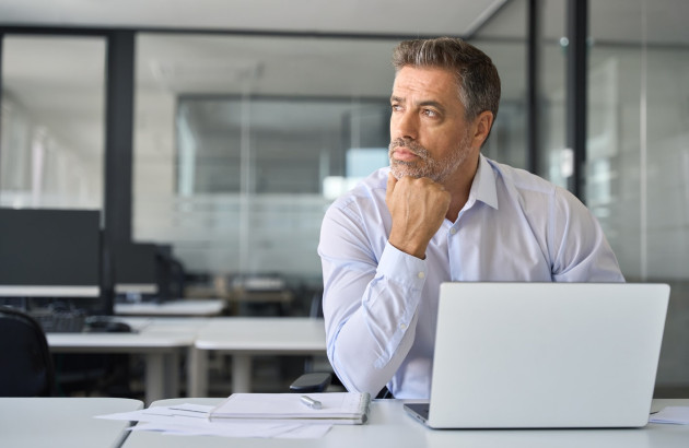 un homme derrière l'écran de son ordinateur qui fait mine de s'interroger