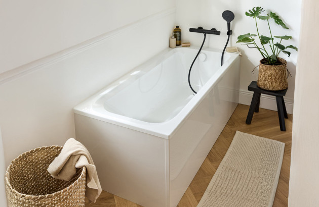 Baignoire rectangulaire compacte installée dans une salle de bains étroite avec décoration scandinave et rangements intégrés.