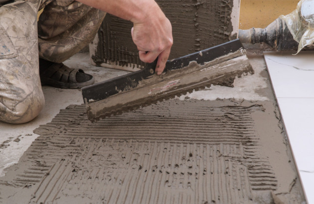 Artisan qui réalise un double encollage de carrelage