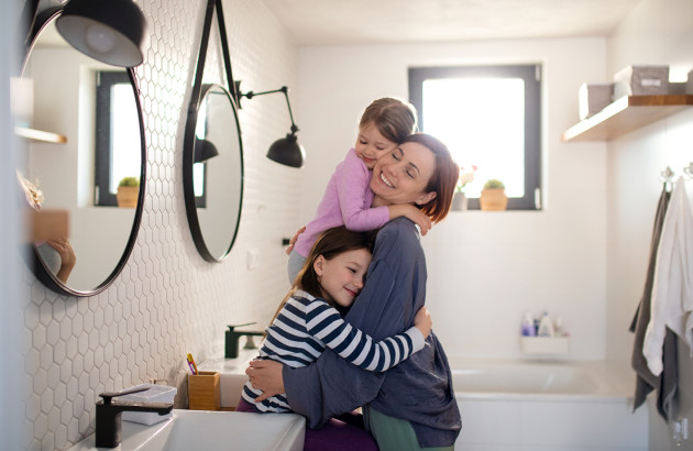 Mère avec ses deux enfants dans une salle de bains familiale moderne avec baignoire.