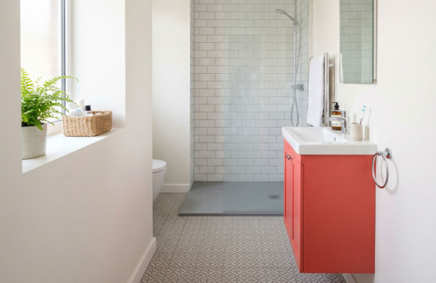 Petite salle de bains optimisée avec meuble rouge corail suspendu et douche à l’italienne compacte.