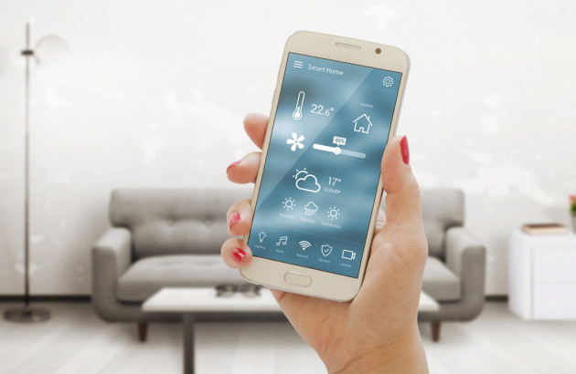Personne qui contrôle la température de son logement avec son téléphone