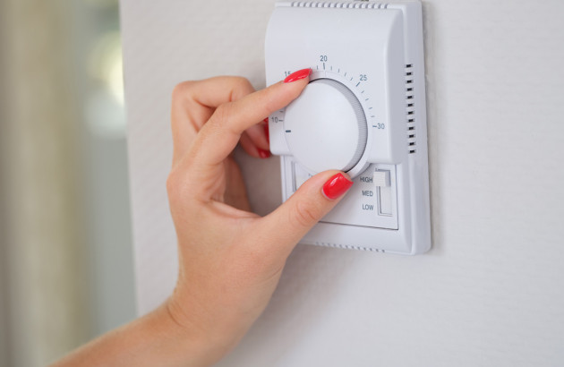 Femme qui utilise un thermostat avec un bouton de réglage sous forme de roue
