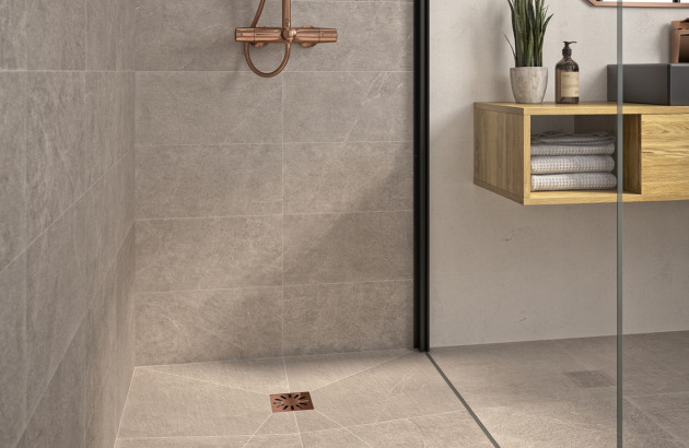 Douche à l’italienne avec receveur carrelé, paroi vitrée et robinetterie finition cuivre.
