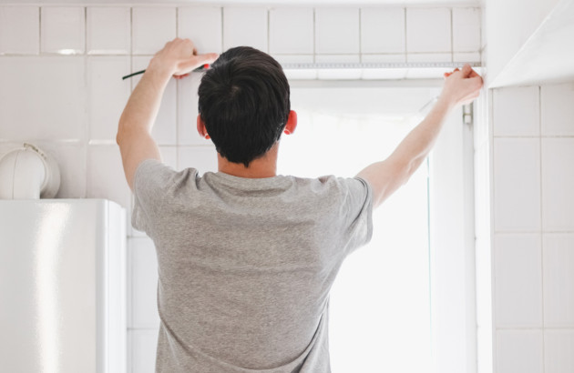 Homme qui mesure l'espace de sa salle de bains