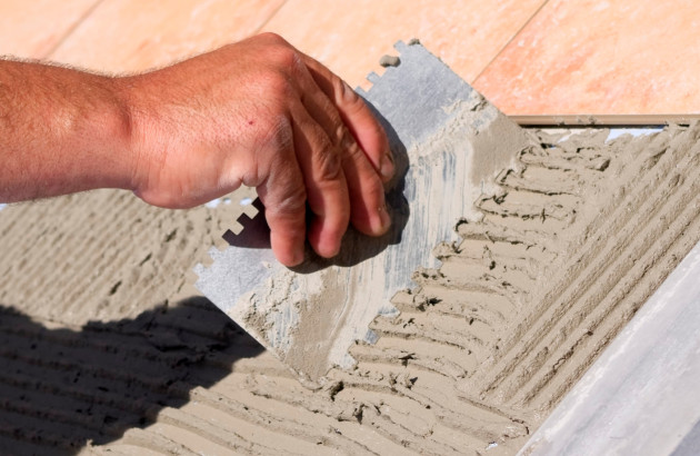 Homme qui utilise un peigne de carrelage pour appliquer du mortier colle