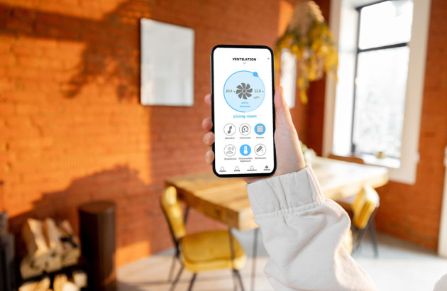 smartphone affichant une application de gestion de la climatisation dans une pièce à la décoration chaleureuse en briques rouges
