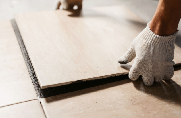 Artisan carreleur qui pose du carrelage sur le sol