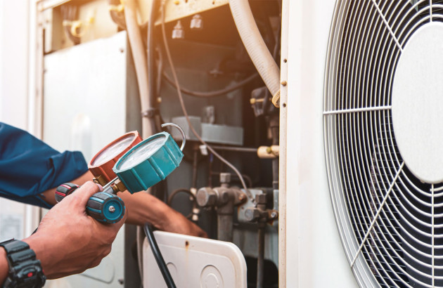 Artisan qui réalise un entretien d'un système de climatisation