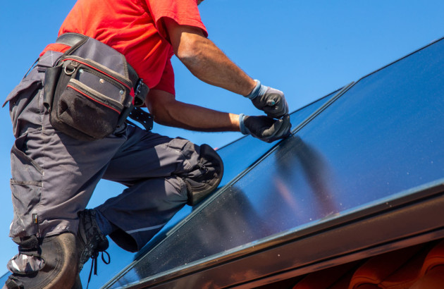 Artisan qui installe un panneau solaire thermique