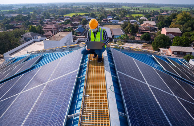 artisan sur le toit d'une maison en train d'installer des panneaux solaires