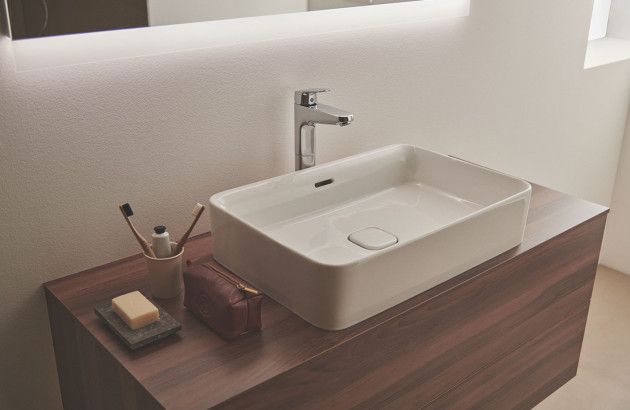 Lavabo rectangulaire en céramique blanche posé sur un meuble suspendu en bois foncé.