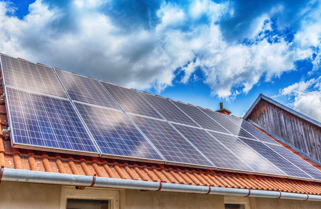 Panneaux photovoltaïques installés sur une toiture en tuiles sous un ciel ensoleillé.