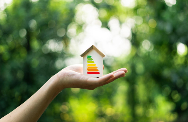 Femme qui tient dans sa main une maisonnette avec un diagramme de performance énergétique