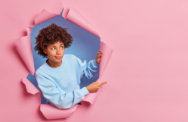 Femme qui sort d'un mur en papier rose