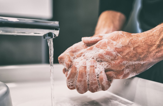 Homme qui se lave les mains sans contact grâce à un robinet infrarouge