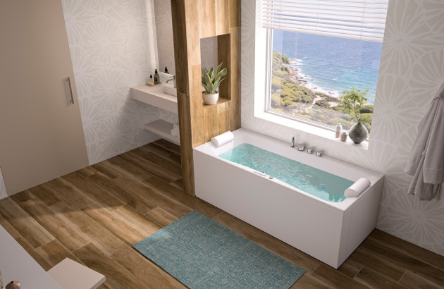 Baignoire massante blanche installée près d’une fenêtre avec vue sur mer.