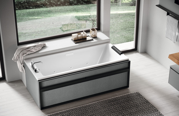Baignoire massante rectangulaire avec habillage noir dans une salle de bains moderne.