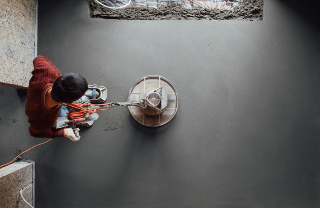 Homme qui utilise une machine pour appliquer du béton