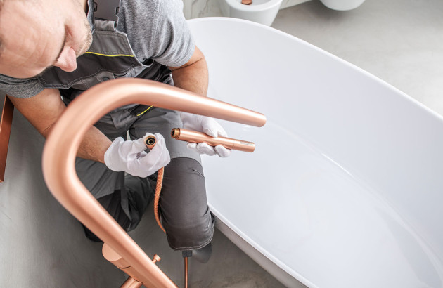 Homme qui installe un mitigeur sur pieds pour une baignoire îlot