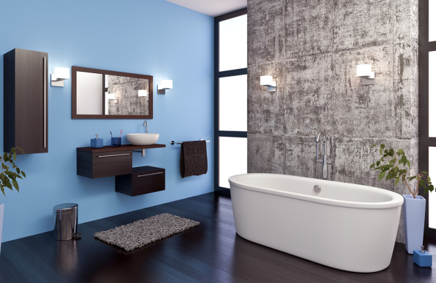 Salle de bains moderne avec baignoire îlot, mur effet béton et meuble vasque suspendu.