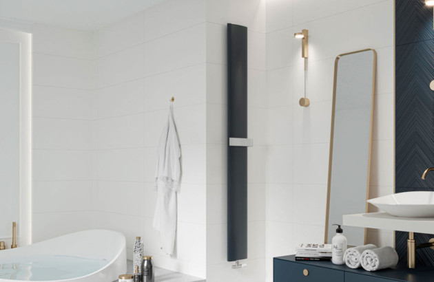Radiateur décoratif vertical noir installé dans une salle de bains élégante avec baignoire îlot et mobilier bleu nuit.