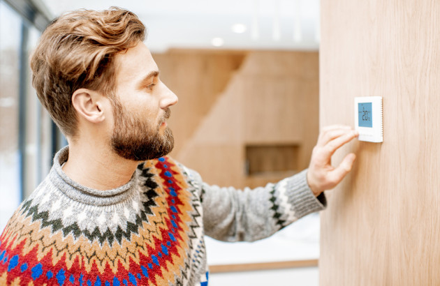Homme qui utilise sont thermostat programmable dans sa maison
