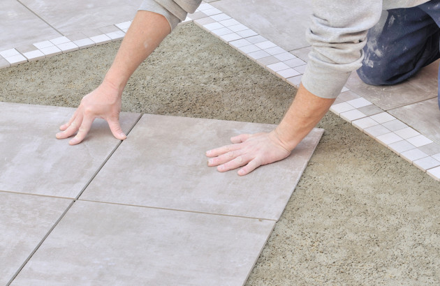 Homme qui pose des carreaux de carrelage au sol
