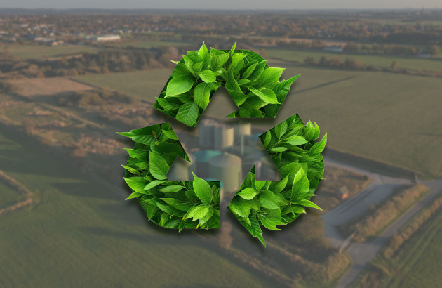 Feuilles qui forment le symbole d'énergie renouvelable avec en fond une ferme de biométhane