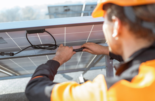 Ouvrier qui s'occupe de brancher des câbles de panneau solaire