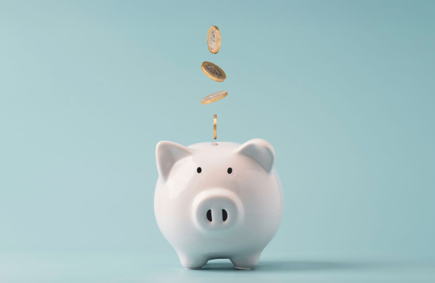 Cochon tirelire avec des pièces qui tombent à l'intérieur sur un fond bleu clair