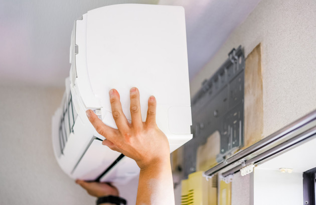 Pose d’une unité intérieure de climatisation lors de travaux d’équipement du logement.