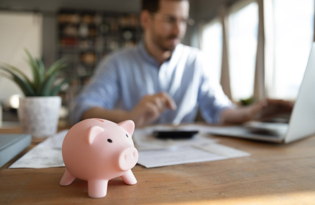 Homme qui travaille sur un bureau avec une tirelire cochon