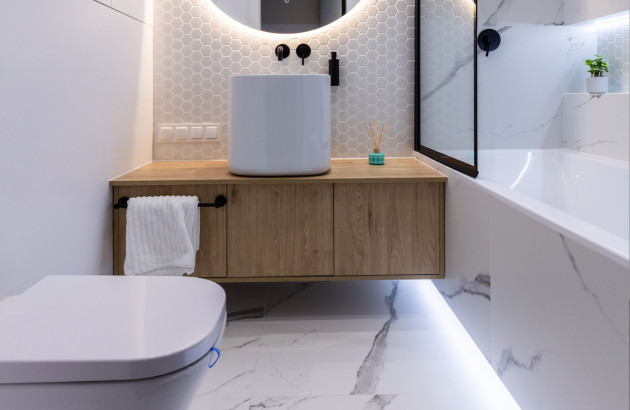 Petite salle de bains avec carrelage blanc imitation marbre et miroir lumineux