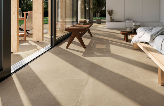 Carrelage XXL effet béton posé dans une chambre avec continuité sur l'extérieur