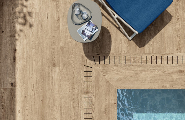 Détail de carrelage imitation bois en extérieur avec finition antidérapante près d’une piscine.