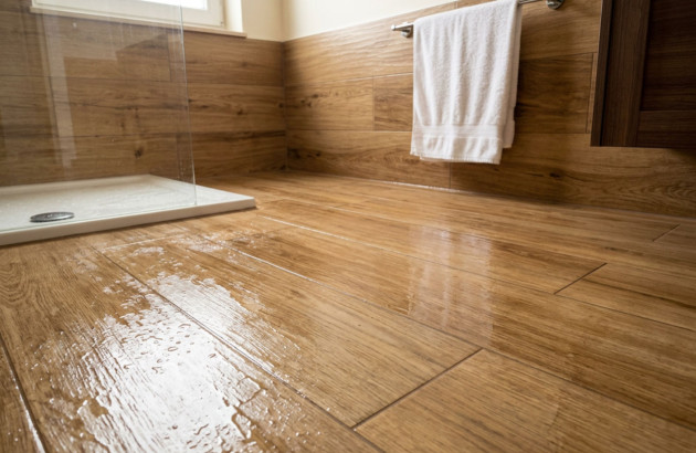Sol et murs de salle de bains en carrelage imitation bois avec douche à l’italienne et effet naturel réaliste.