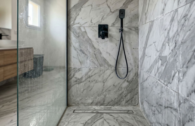 Douche à l'italienne avec un carrelage effet marbre abimé par le calcaire