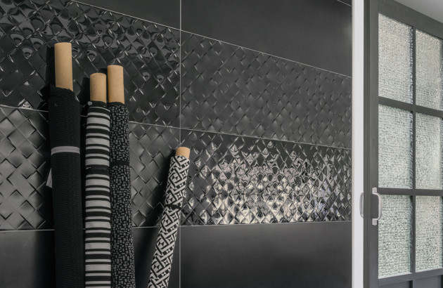 Carrelage mural noir brillant à motifs géométriques, posé en crédence de cuisine contemporaine, illustrant une tendance durable et élégante du carrelage noir en 2026.