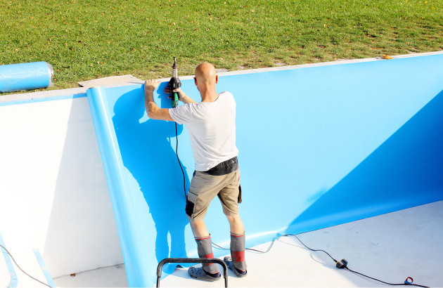 ouvrier effectuant la pose de liner dans une piscine