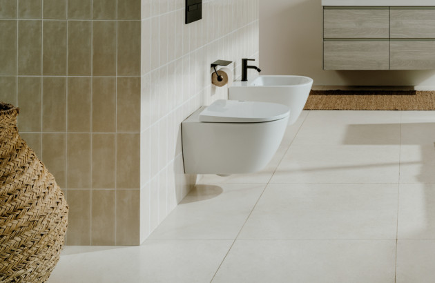 Revêtement mural beige et sol assorti pour des WC et bidet à l'ambiance zen et naturelle avec accessoires noirs.