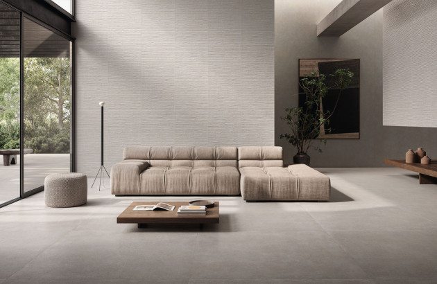 Salon moderne avec canapé jaune, table basse noire et carrelage grand format gris clair au sol.